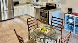A modern kitchen with white cabinets, stainless steel appliances, a glass dining table, and a ceiling fan. - 3-bedroom house Near Masssy's boat ramp, Paradise Grill & Pot N Nets & Baywood (Millsboro)
