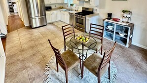 A modern kitchen with white cabinets, stainless steel appliances, and a dining area with a glass table and wooden chairs. - 3-bedroom house Near Masssy's boat ramp, Paradise Grill & Pot N Nets & Baywood (Millsboro)