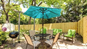 Eine Terrasse mit Tisch, Stühlen, einem Grill und einem Holzzaun.