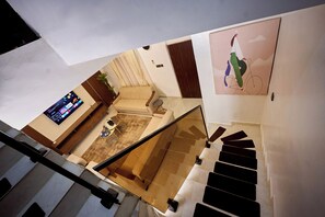 A staircase leading to a living area with a sofa, a coffee table, and a TV. - AB Homes (Abuja)