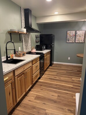 A kitchen with wooden cabinets, a black refrigerator, a microwave, and a sink.