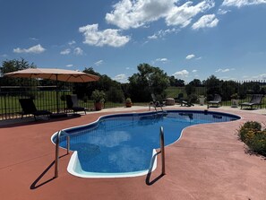 A swimming pool with a curved edge, surrounded by lounge chairs and a fence. - A Beautiful Farmhouse Retreat For Two in Limestone TN (Limestone)