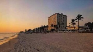 Une plage avec un hôtel, des palmiers et un ciel dégagé.