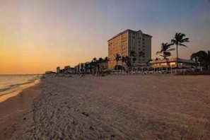 A beach with a hotel, palm trees, and a clear sky. - Naples House with Full Kitchen & Patio - Perfect for Families! (Naples)