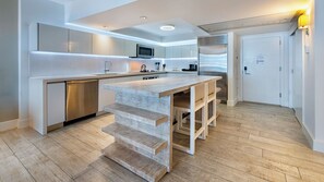 Eine moderne Küche mit Kochinsel, integrierten Geräten und Holzboden.