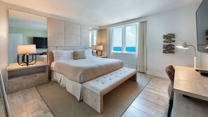 Ein modernes Hotelzimmer mit einem großen Bett, Nachttischlampen, einem Flachbildfernseher und Meerblick.