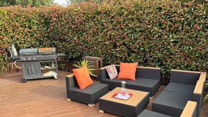 An outdoor patio with wicker furniture, a grill, and a hedge in the background. - Family home with a pool near the village, close to the beaches (Saint-Cyr-sur-Mer)