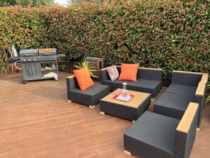 An outdoor patio with wicker furniture, a grill, and a hedge in the background. - Family home with a pool near the village, close to the beaches (Saint-Cyr-sur-Mer)