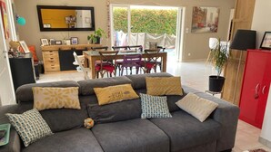 A living room with a grey sofa, a dining table, and a red cabinet. - Family home with a pool near the village, close to the beaches (Saint-Cyr-sur-Mer)