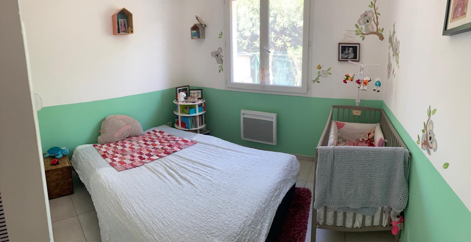Une chambre d’enfant avec un lit, un berceau et des décorations murales.