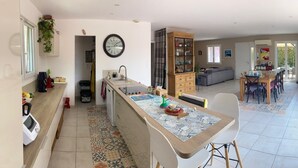 A modern kitchen with a central island, a dining area with a table and chairs, and a living room with a sofa and a TV. - Family home with a pool near the village, close to the beaches (Saint-Cyr-sur-Mer)