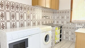 Eine kleine Küche mit Waschmaschine, Backofen und Holzschränken.