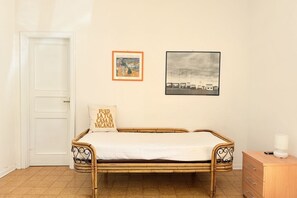 Habitació amb un llit individual, un aparador de fusta i dues imatges emmarcades a la paret.