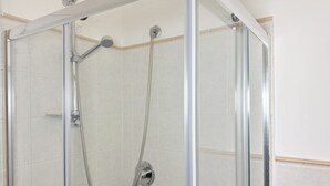 Eine Duschkabine mit Handbrause und fest installierter Duschkopf.