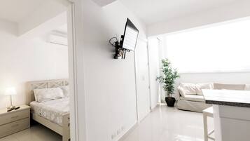 Una habitación de hotel moderna con cama, mesita de noche, lámpara y una planta en maceta.