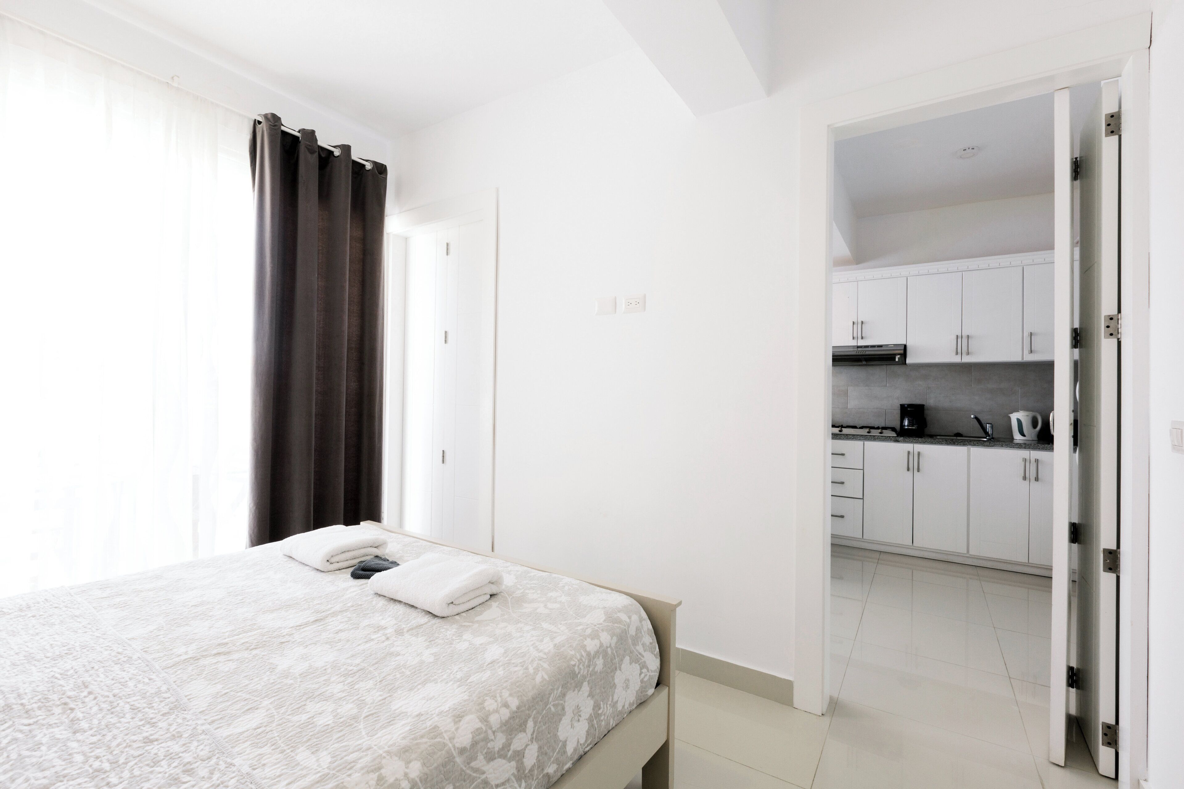 Ein Schlafzimmer mit Bett, Bad und Küche, die durch eine offene Tür sichtbar sind.