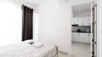Ein Schlafzimmer mit Bett, Bad und Küche, die durch eine offene Tür sichtbar sind.