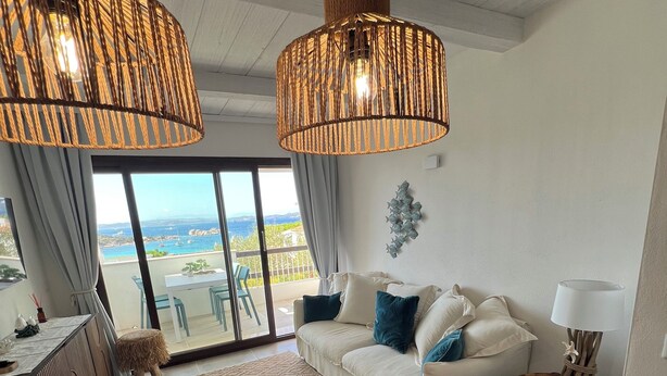 A modern living room with a sofa, a dining table, and a view of the sea. - The View 108 - Stylish apartment near the beach in Baja Sardinia (Baja Sardinia)
