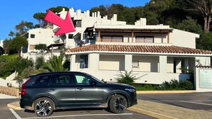 A parking lot with a dark-colored SUV parked in front of a building with a tiled roof and white walls. - The View 108 - Stylish apartment near the beach in Baja Sardinia (Baja Sardinia)