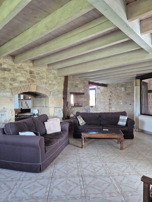 A rustic interior with stone walls, wooden beams, two sofas, a coffee table, and a tiled floor. - Quiet, unoverlooked country house with private saltwater pool (Lacaussade)