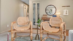 A room with two wicker chairs, a small table, a mirror, and a door leading to a bathroom. - Hot Tub, Sauna & Game Room Mountain-View Home (Westminster)