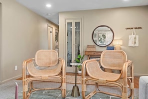 A room with two wicker chairs, a small table, a mirror, and a door leading to a bathroom. - Hot Tub, Sauna & Game Room Mountain-View Home (Westminster)