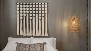 A bed with white linens, a decorative wall hanging, and a woven light fixture. - Hot Tub, Sauna & Game Room Mountain-View Home (Westminster)