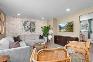 A living room with a sofa, two wicker chairs, a coffee table, a TV, and a large plant. - Hot Tub, Sauna & Game Room Mountain-View Home (Westminster)