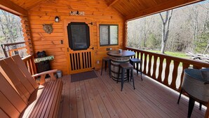 A wooden cabin with a deck, a welcome sign, a bear statue, and a Sasquatch sign.