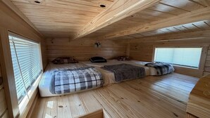 A cabin with a loft bed, a small desk, and a window.