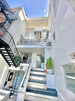 Un edificio de varios niveles con escaleras, balcones y una puerta que indica '27-130'.