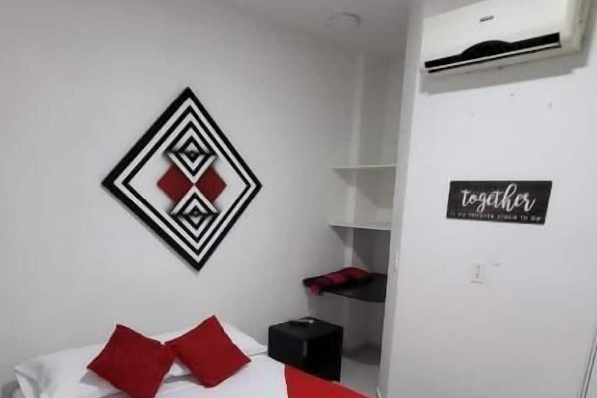 A bedroom with a bed, a wall-mounted air conditioner, a shelf unit, and a sign with the word 'Together'.