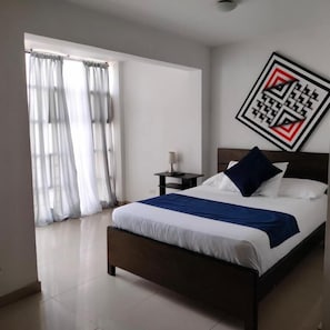 A bedroom with a bed, curtains, a nightstand, and a wall art piece.