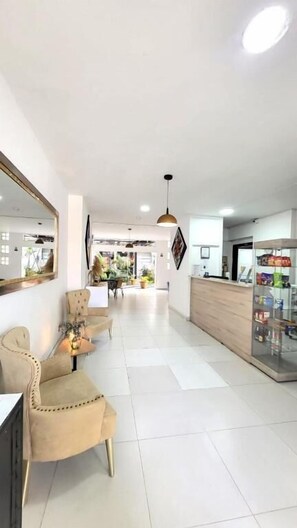 A hotel lobby with a reception desk, seating area, and a large mirror.
