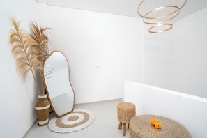 A modern bathroom with a round mirror, a woven stool, and a decorative vase with pampas grass. - Cozzy  Ayura Villa Legian (denpasar)