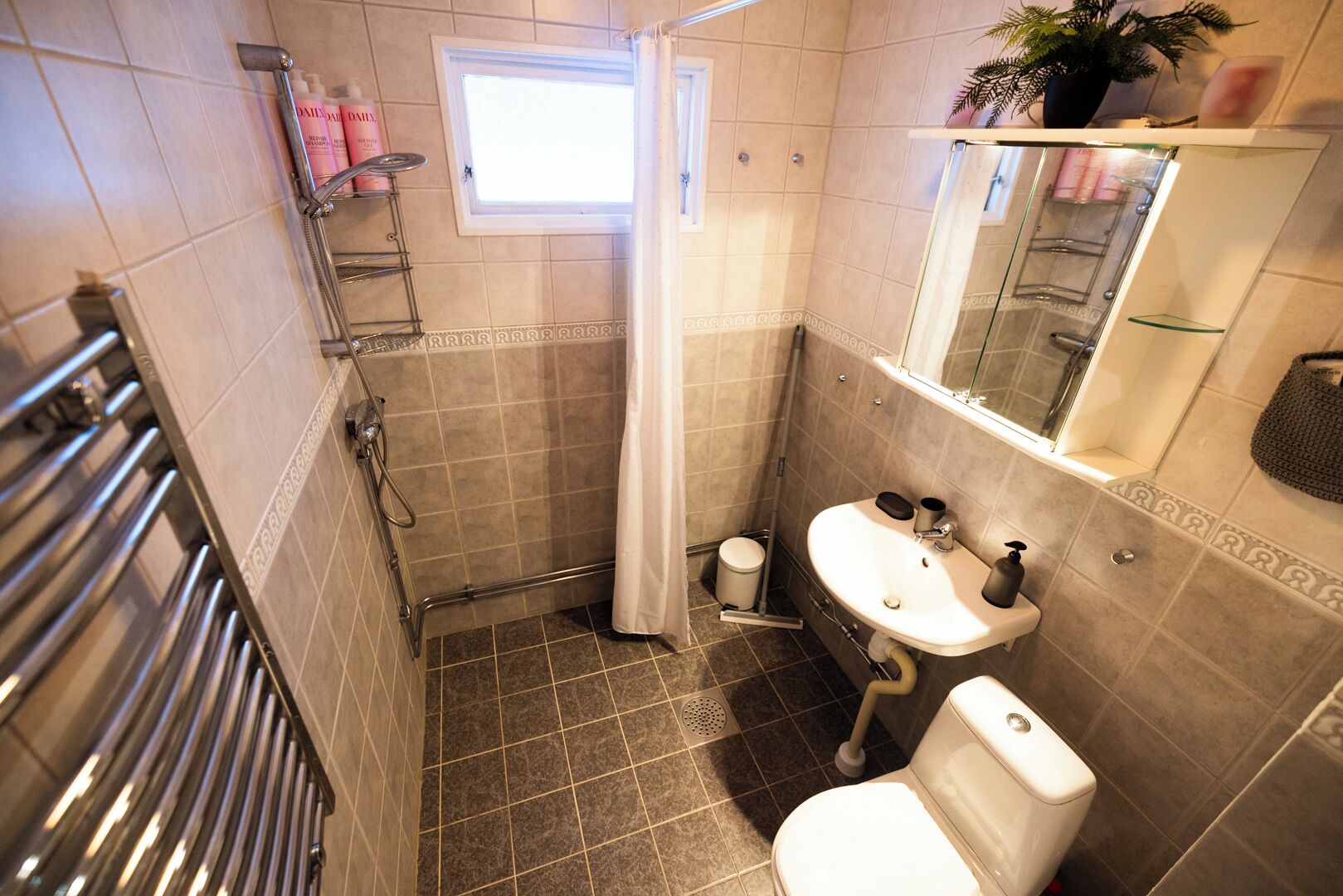 Un bagno con doccia, servizi igienici, lavandino e una finestra.