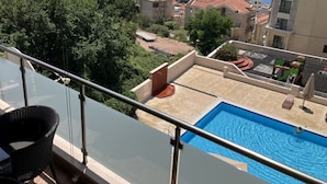 Ein Wohngebiet mit Schwimmbad, einem Balkon mit Glasgeländer und Gebäuden mit roten Ziegeldächern.