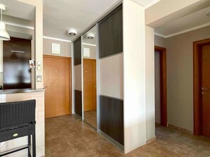 Un pasillo con una puerta corredera de vidrio, una puerta de madera y una lámpara fijada a la pared.