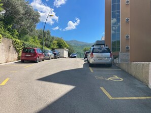 Un estacionamiento con coches, un edificio de amplios ventanales y una montaña al fondo.