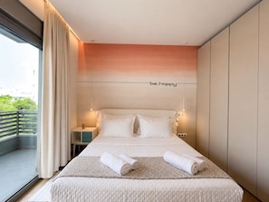 Et moderne hotelværelse med en stor seng, udsigt til grøn natur og et skilt på væggen med teksten 'be happy'.