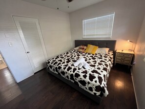 A bedroom with a bed, a nightstand, a window with blinds, a door, and a light switch. - Cute Pool home in Jungle Terrace - 3/1  fast WiFi, 35 days minimu - 10' to beach (St. Petersburg)
