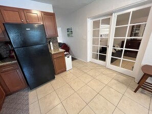 A kitchen with a refrigerator, a dishwasher, and a sliding glass door leading to a dining area. - Cute Pool home in Jungle Terrace - 3/1  fast WiFi, 35 days minimu - 10' to beach (St. Petersburg)