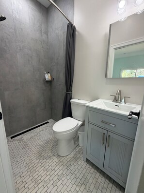 Ein Badezimmer mit Dusche, Toilette, Waschbecken und Schrank.