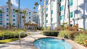 A hotel with a swimming pool, palm trees, and a thatched-roof gazebo. - Cozy 1-bedroom apartment in charming Orlando (Orlando)