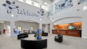 A spacious lobby with a central seating area, a reception desk, and a large wall mural with a 'Welcome' sign. - Cozy 1-bedroom apartment in charming Orlando (Orlando)