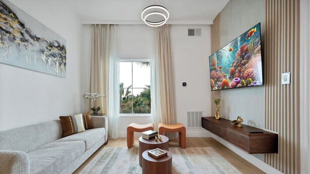 A modern living room with a sofa, two round coffee tables, a TV, and a large window. - Cozy 1-bedroom apartment in charming Orlando (Orlando)
