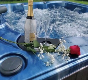 A hot tub with a bottle of champagne, a glass, and a rose on ice. - BUNGALOW DE SAINT JACQUES (Saint-François)