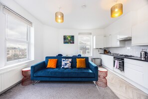 Eine moderne Wohnung mit einem blauen Sofa, einer Küche und großen Fenstern.