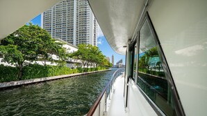 A river with a boat, buildings, and trees along the banks. - Stay Aboard a Vintage Hatteras 53' Motor Yacht in Aventura-A Unique Experience! (Aventura)