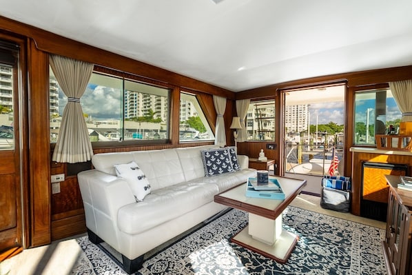 A modern interior with a sofa, coffee table, and large windows offering a marina view.